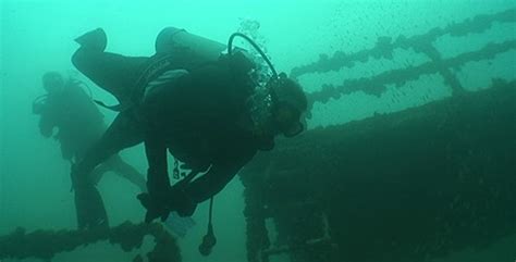 single scuba diver near sunken wreckage